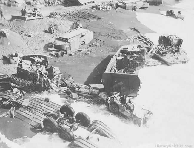 Iwo Jima. Note the rolled over DUKW in front of wrecked jeep.